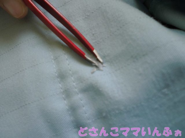 作業服の刺繍を毛抜きで糸を取る